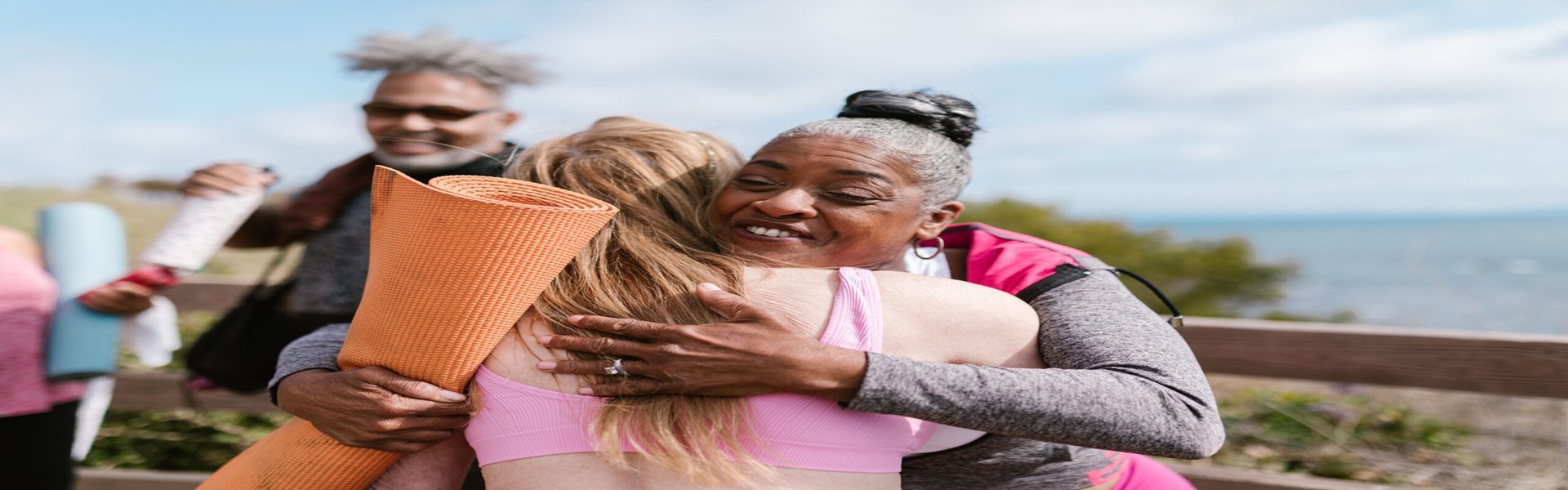 Active older adults embracing after outdoor fitness class, promoting healthy lifestyle supported by internal medicine care in Shenandoah and The Woodlands TX
