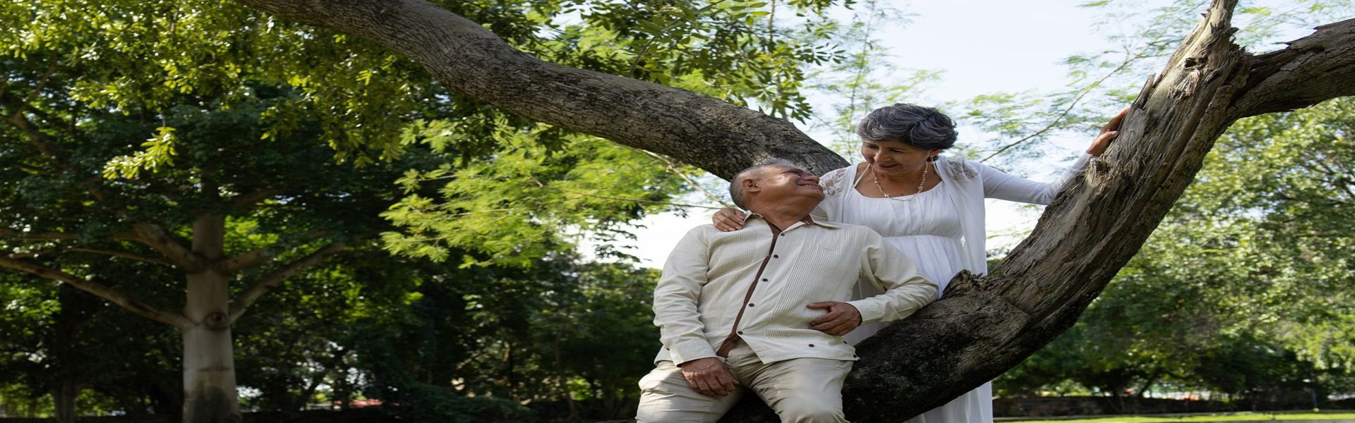 Happy older couple laughing together outdoors by a tree, representing healthy aging with internal medicine care in Shenandoah and The Woodlands TX